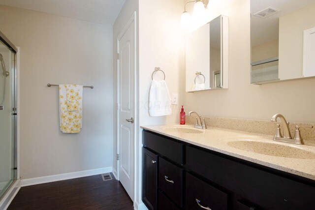 bathroom with hardwood / wood-style flooring, vanity, and an enclosed shower