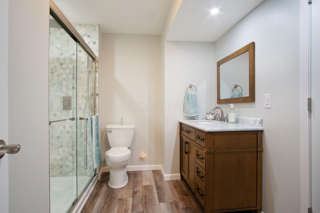 bathroom with an enclosed shower, hardwood / wood-style floors, vanity, and toilet