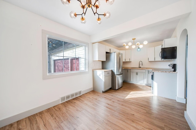 kitchen with stainless steel fridge, hanging light fixtures, white cabinets, a chandelier, and light wood-type flooring