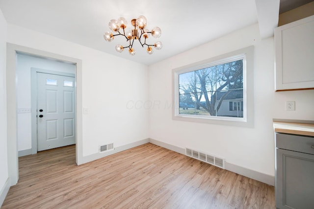 unfurnished dining area with light hardwood / wood-style floors and a chandelier