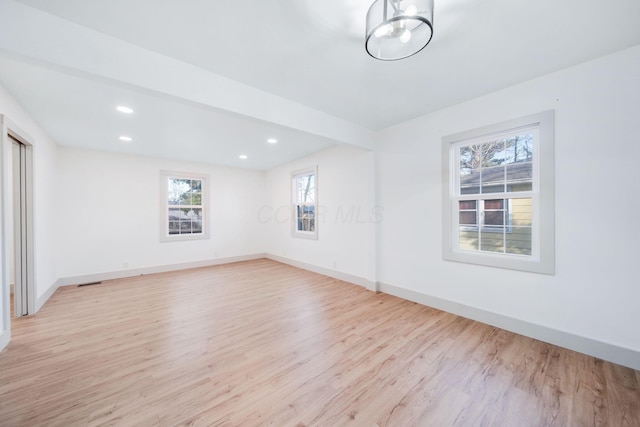 spare room featuring beam ceiling and light hardwood / wood-style flooring