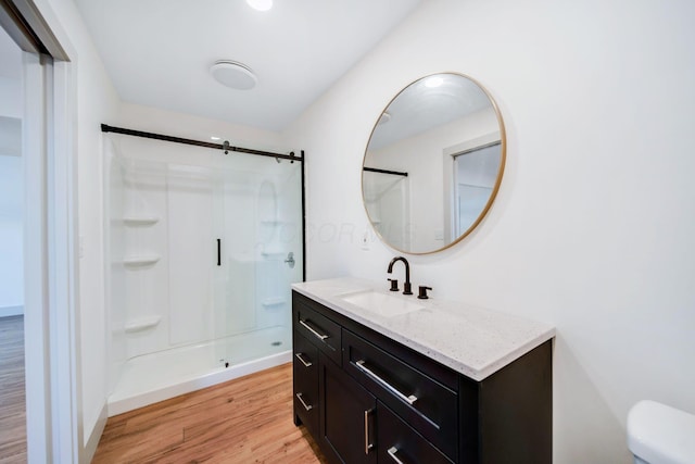 bathroom featuring wood-type flooring, toilet, an enclosed shower, and vanity