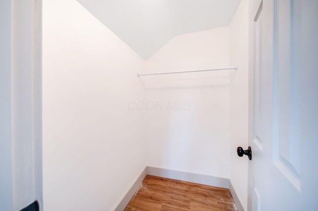 walk in closet featuring hardwood / wood-style floors and vaulted ceiling