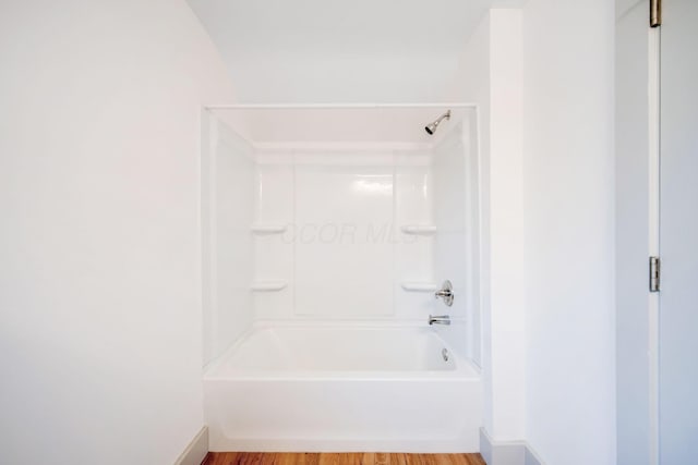 bathroom featuring hardwood / wood-style flooring and washtub / shower combination