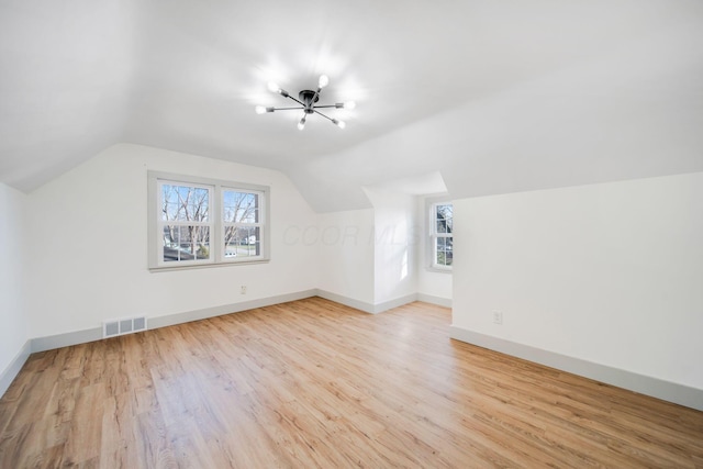 additional living space featuring lofted ceiling, a wealth of natural light, and light hardwood / wood-style floors