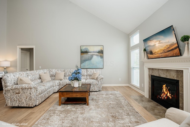 living room with high vaulted ceiling, a fireplace, and hardwood / wood-style floors