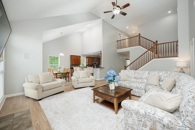 living room with light hardwood / wood-style flooring, high vaulted ceiling, and ceiling fan