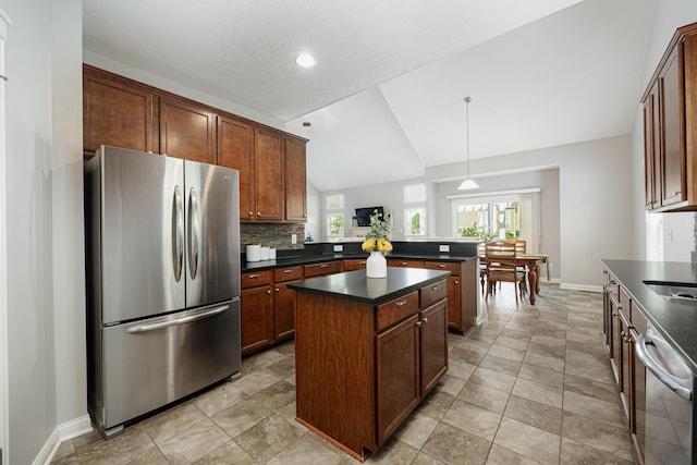 kitchen with lofted ceiling, a center island, stainless steel refrigerator, dishwashing machine, and backsplash