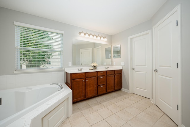 bathroom with tiled tub, vanity, and tile patterned floors