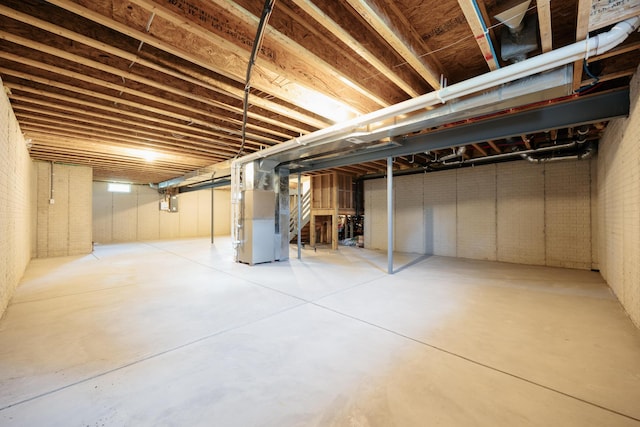 basement featuring brick wall and heating unit