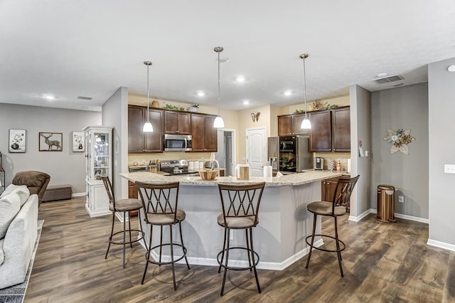 kitchen featuring dark brown cabinets, stainless steel appliances, a breakfast bar, and hanging light fixtures