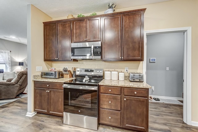 kitchen with dark brown cabinets, light hardwood / wood-style flooring, and stainless steel appliances