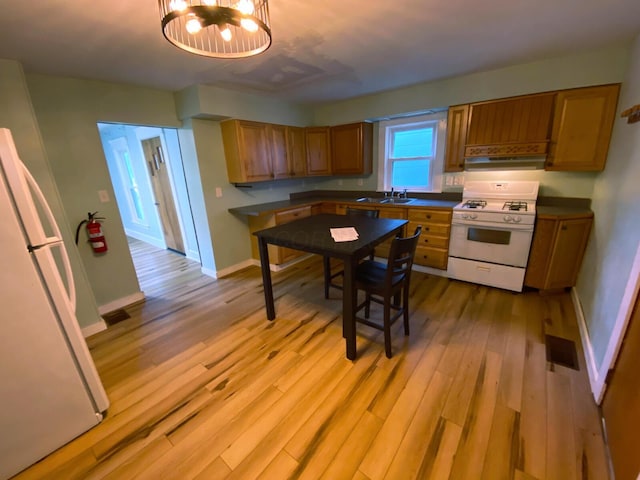 kitchen featuring sink, white appliances, light hardwood / wood-style flooring, and a notable chandelier