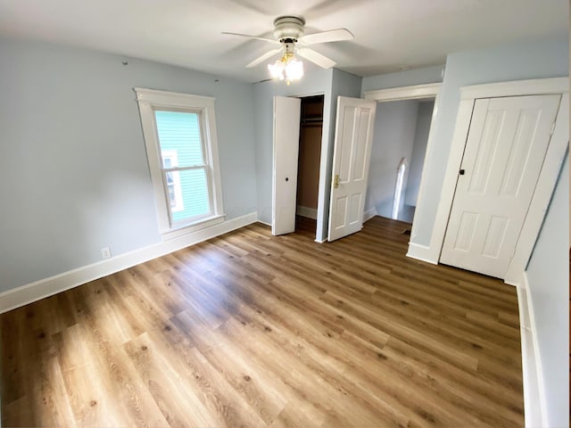 unfurnished bedroom featuring multiple closets, ceiling fan, and light hardwood / wood-style floors