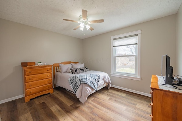 bedroom featuring ceiling fan, hardwood / wood-style flooring, and a textured ceiling