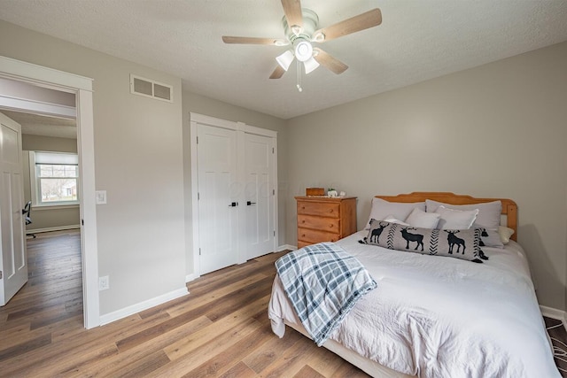 bedroom with ceiling fan, hardwood / wood-style flooring, a closet, and a textured ceiling