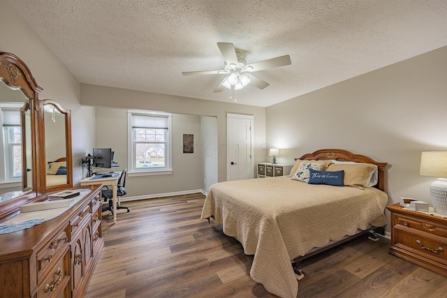 bedroom featuring dark wood-type flooring, ceiling fan, and a textured ceiling