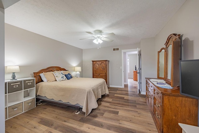 bedroom with wood-type flooring, ceiling fan, and a textured ceiling