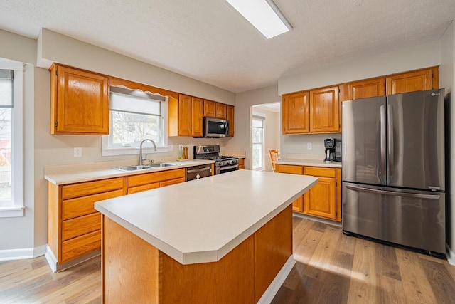 kitchen with stainless steel appliances, a center island, sink, and light wood-type flooring