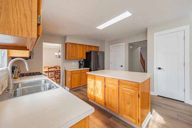 kitchen with sink, light hardwood / wood-style floors, stainless steel refrigerator, and a kitchen island