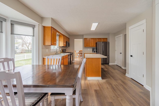 kitchen with sink, a center island, light hardwood / wood-style flooring, a textured ceiling, and appliances with stainless steel finishes