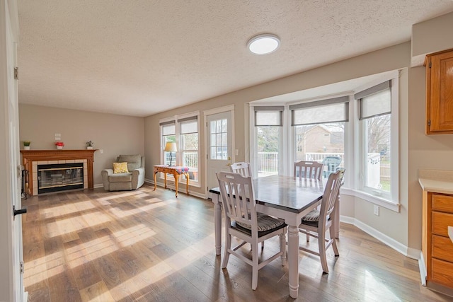 dining area with a fireplace, a textured ceiling, and light wood-type flooring