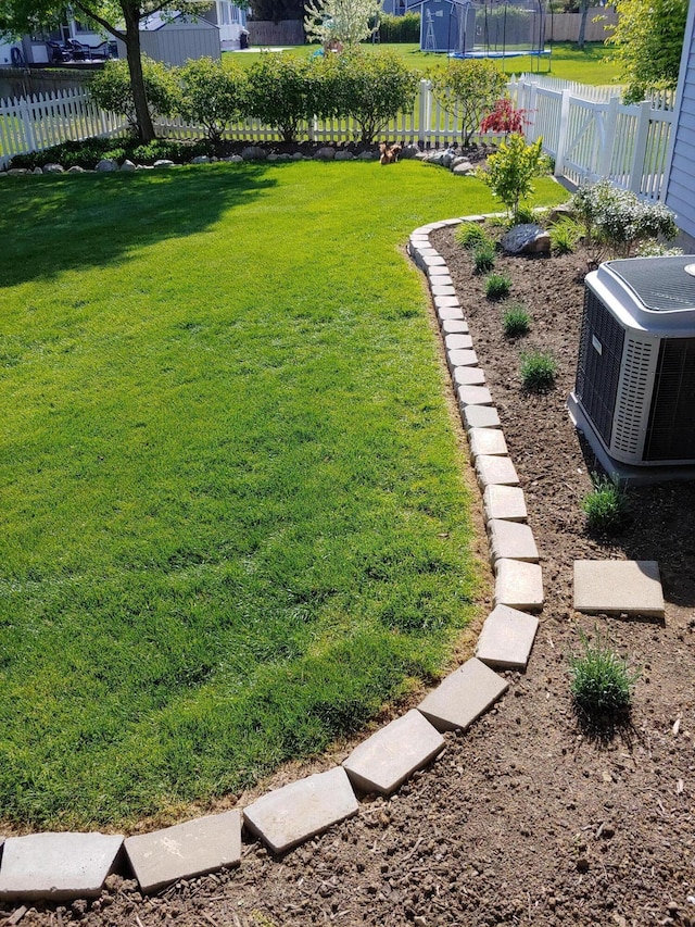 view of yard featuring a trampoline and central AC unit