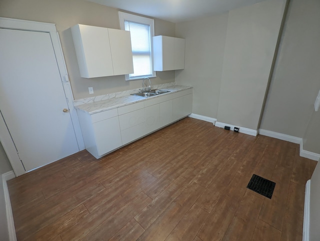 kitchen featuring hardwood / wood-style flooring, sink, and white cabinets