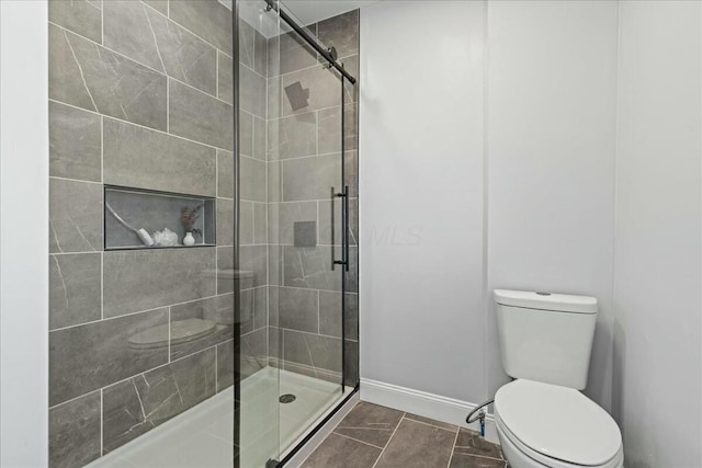 bathroom featuring toilet, an enclosed shower, and tile patterned flooring