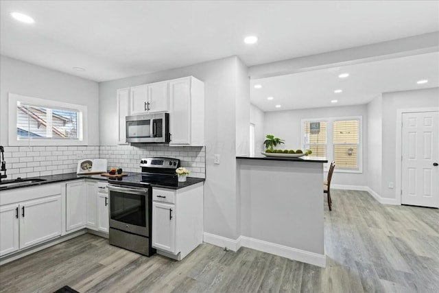 kitchen featuring sink, tasteful backsplash, kitchen peninsula, stainless steel appliances, and white cabinets