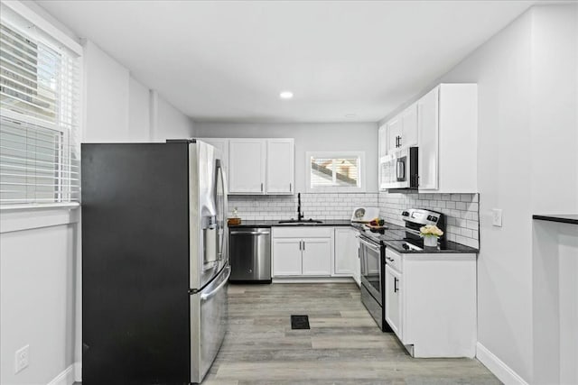 kitchen featuring sink, backsplash, white cabinets, and appliances with stainless steel finishes