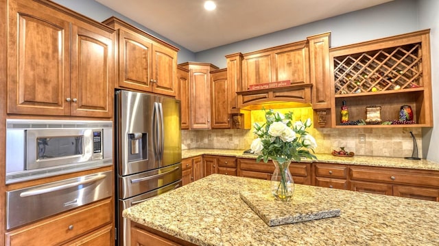 kitchen featuring light stone counters, appliances with stainless steel finishes, and decorative backsplash