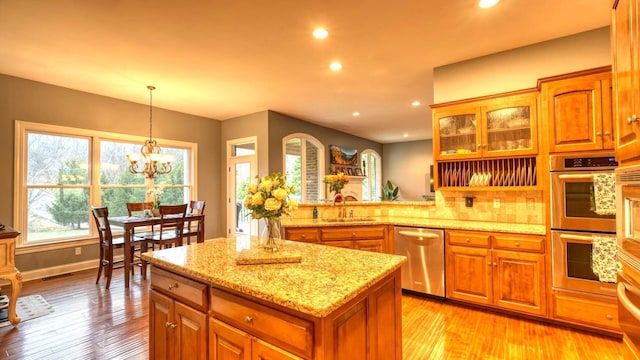 kitchen with stainless steel appliances, sink, pendant lighting, and light hardwood / wood-style flooring