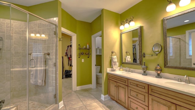 bathroom with tile patterned flooring, vanity, a shower with door, and toilet