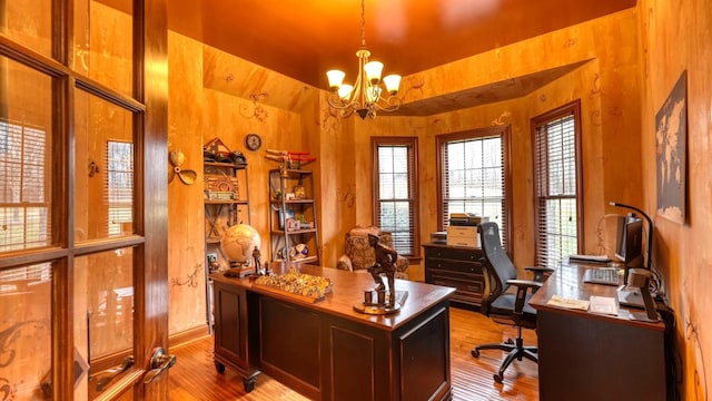 home office with a notable chandelier and light hardwood / wood-style flooring