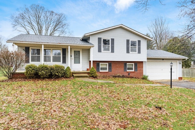 tri-level home with a garage, a front yard, and covered porch