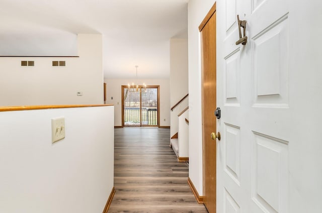 hall featuring an inviting chandelier and dark wood-type flooring