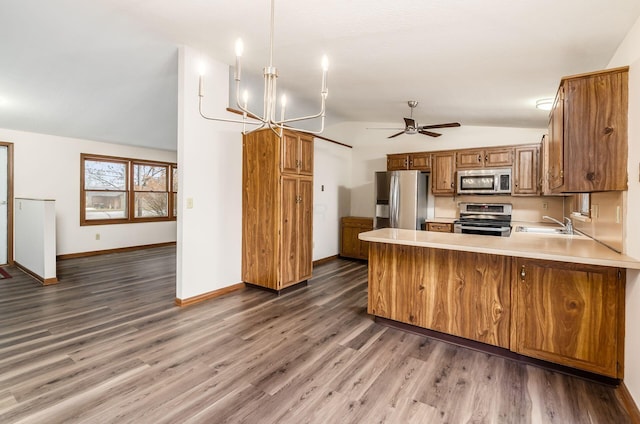 kitchen with sink, appliances with stainless steel finishes, decorative light fixtures, vaulted ceiling, and kitchen peninsula