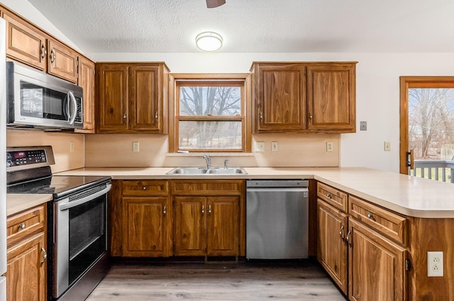 kitchen featuring sink, a textured ceiling, dark hardwood / wood-style floors, kitchen peninsula, and stainless steel appliances