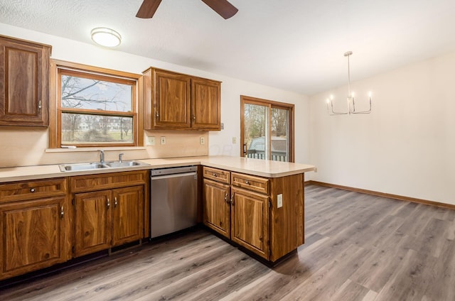 kitchen featuring sink, decorative light fixtures, stainless steel dishwasher, dark hardwood / wood-style floors, and kitchen peninsula