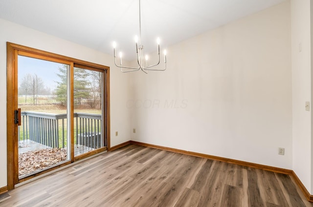 unfurnished dining area with hardwood / wood-style floors and an inviting chandelier