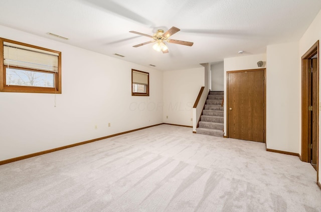 basement with ceiling fan and light carpet