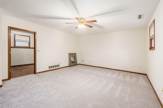 carpeted spare room featuring a textured ceiling and ceiling fan