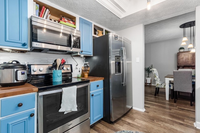 kitchen featuring dark wood-type flooring, blue cabinets, wooden counters, appliances with stainless steel finishes, and pendant lighting