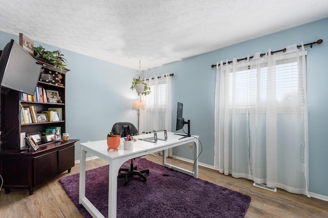 office with light hardwood / wood-style flooring and a textured ceiling