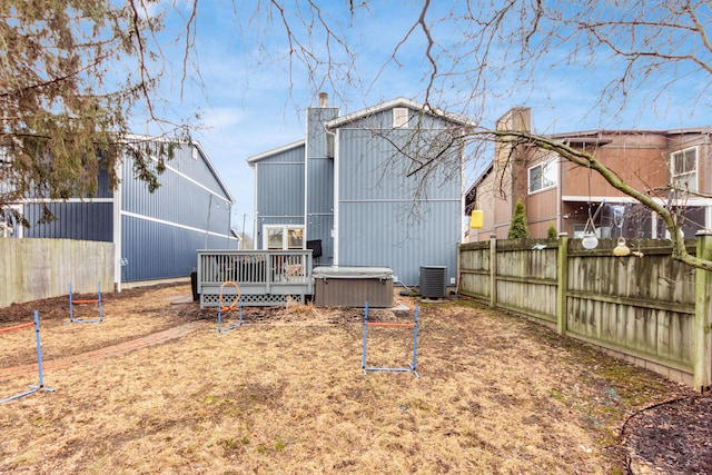 back of house with a hot tub, cooling unit, and a deck