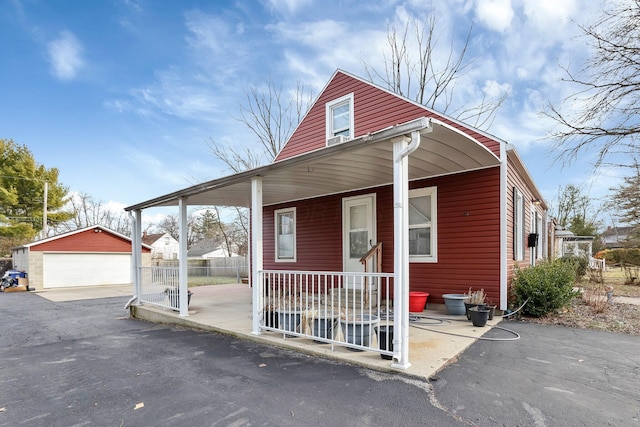 view of front of home featuring a garage, a porch, and an outbuilding