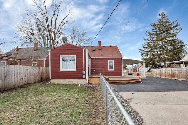 rear view of house featuring a wooden deck and a lawn