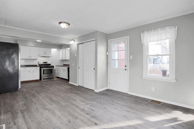 kitchen featuring stainless steel appliances, white cabinetry, tasteful backsplash, and light hardwood / wood-style floors