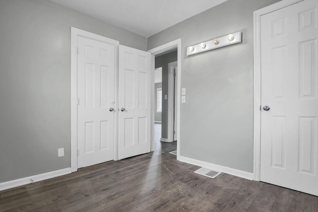 unfurnished bedroom featuring dark hardwood / wood-style floors and a closet